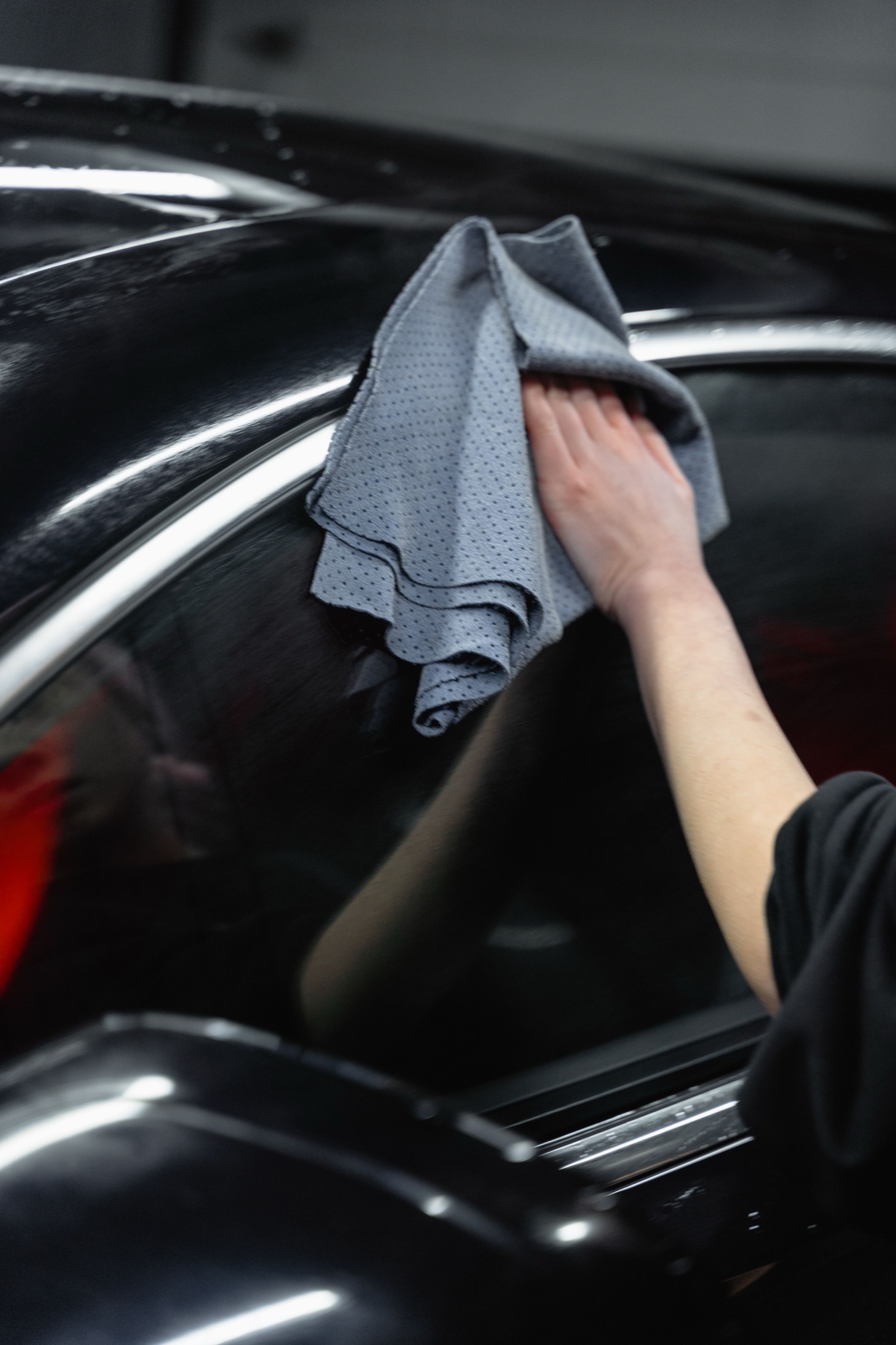 Detailer wiping the finish of a black car